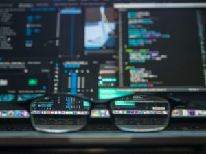 Lunettes reflétant le code informatique sur un écran, idéales pour les thèmes technologiques et de programmation.